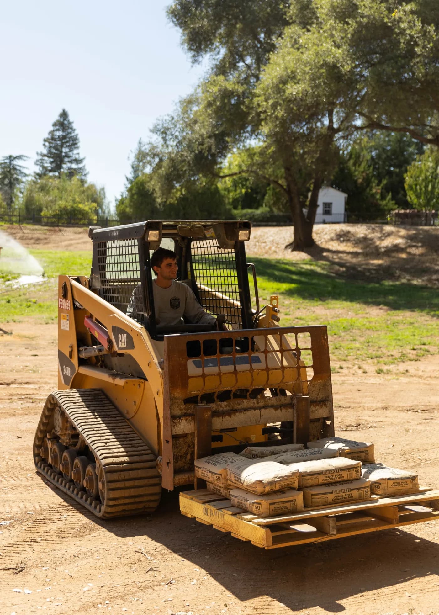 Johnny operating a skid steer to move jobsite materials