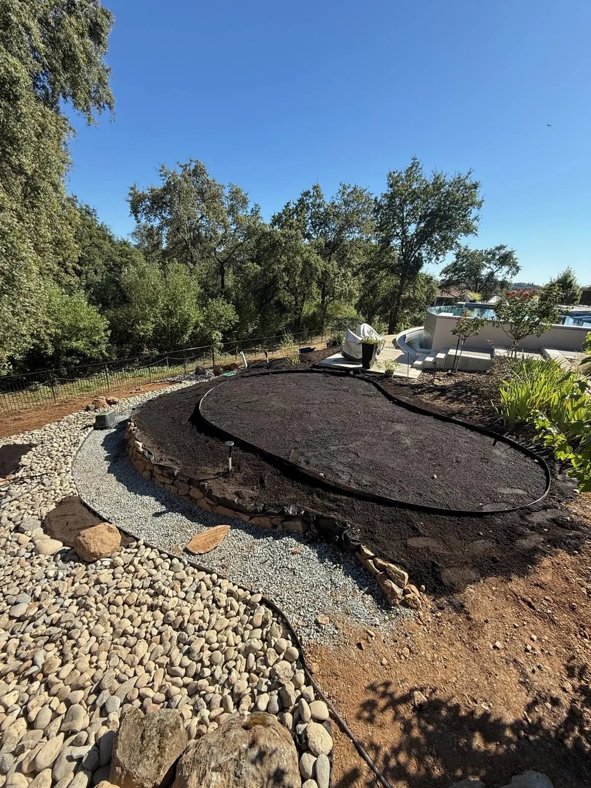 A curved stone border and gravel path in a finished landscape